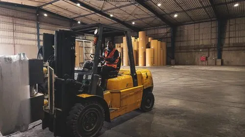Forklift operator transporting a paper roll in the warehouse