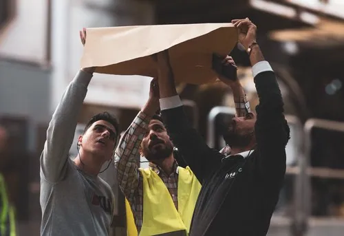 Team members holding a paper sample above their heads