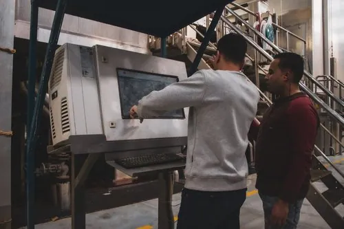 Two mill team members checking the machine control panel