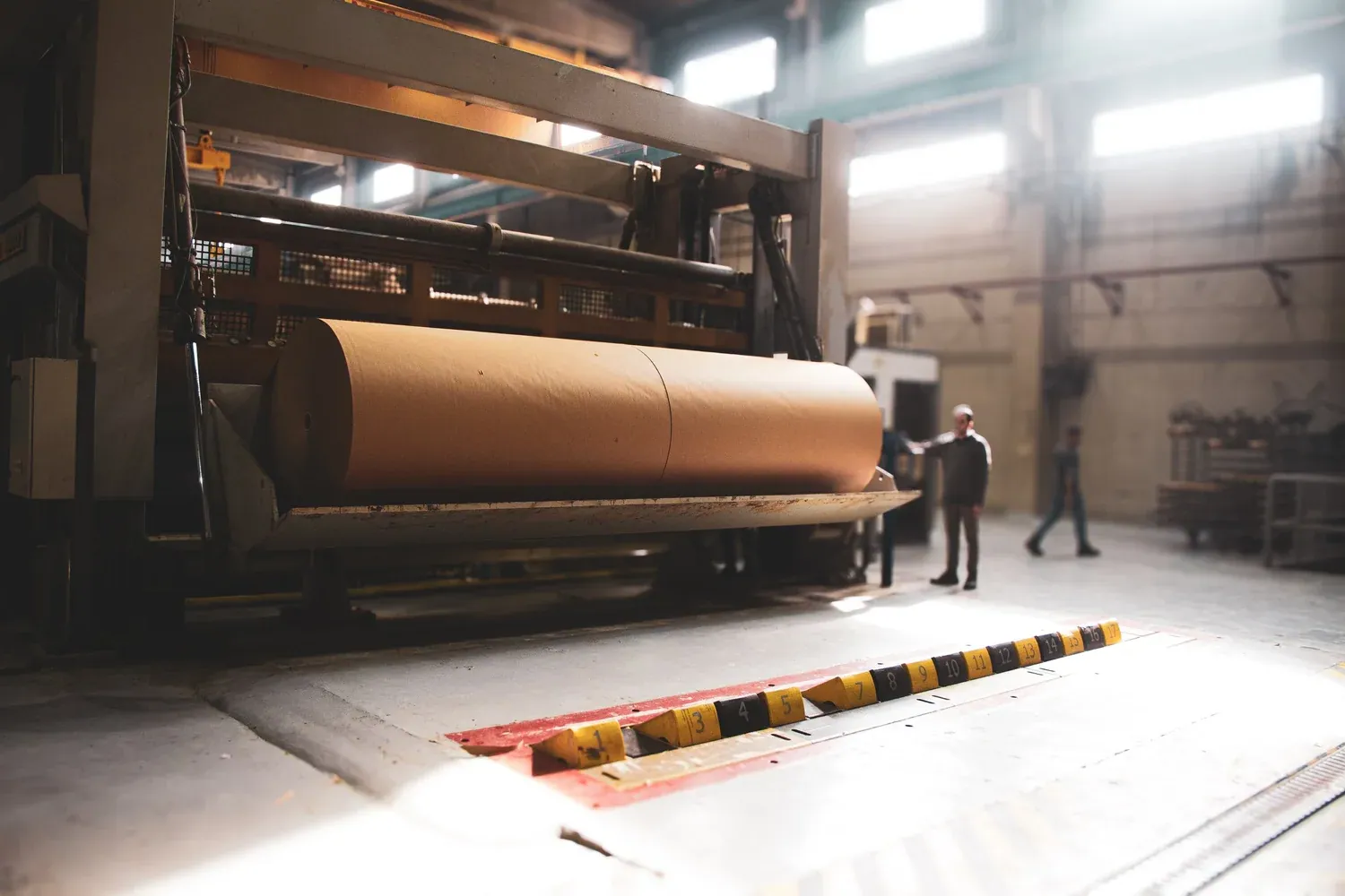 Mill team beside a large paper roll on production machinery